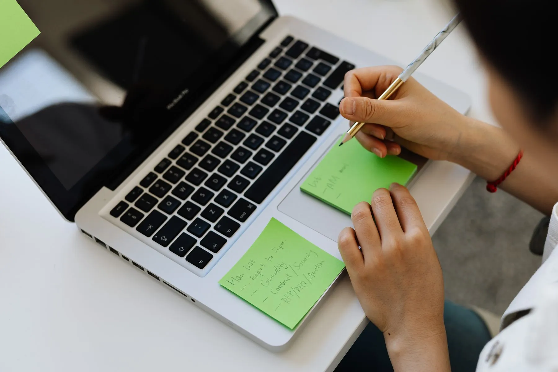 A person making notes on sticky notes beside a laptop