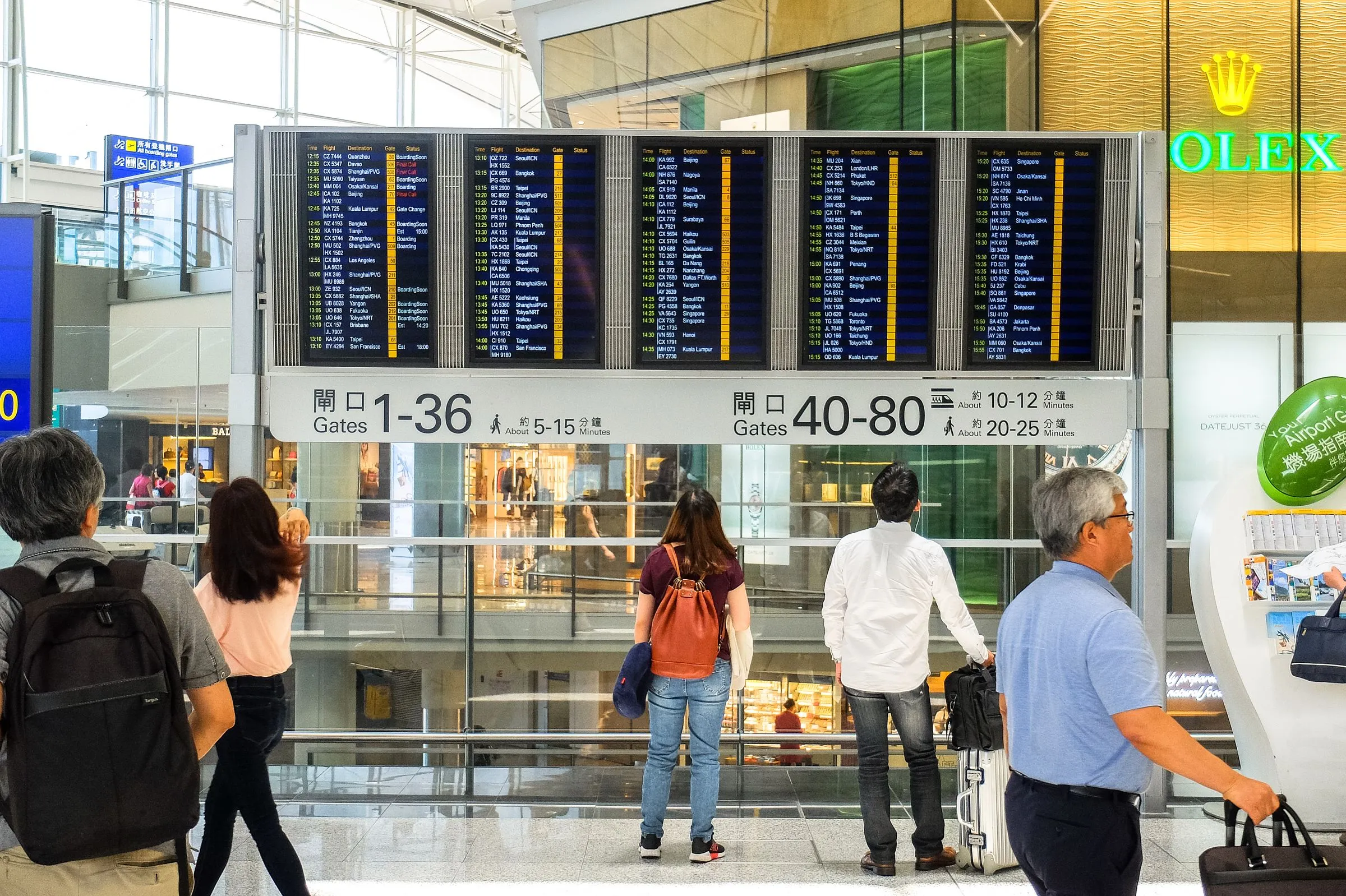 Travellers reading a departures board in an airport terminal