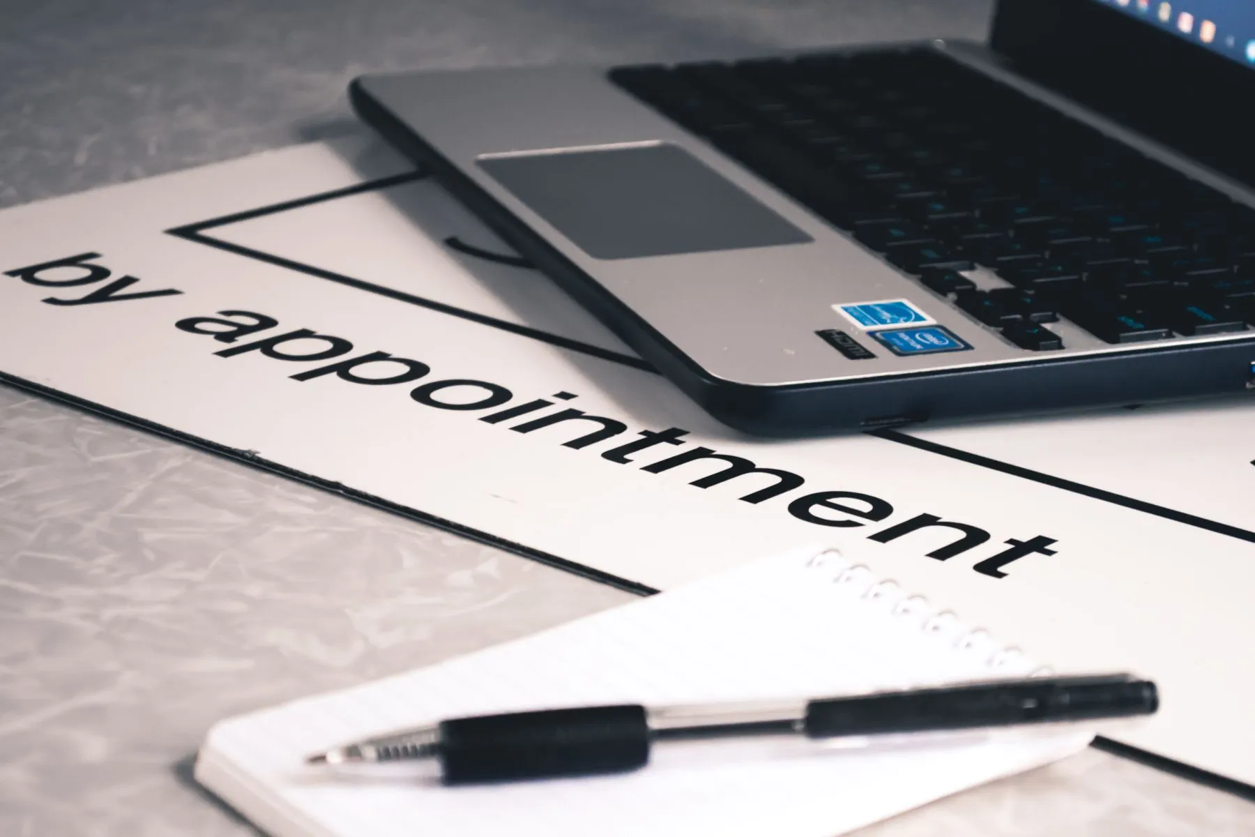A "by appointment" sign beside a laptop and notepad