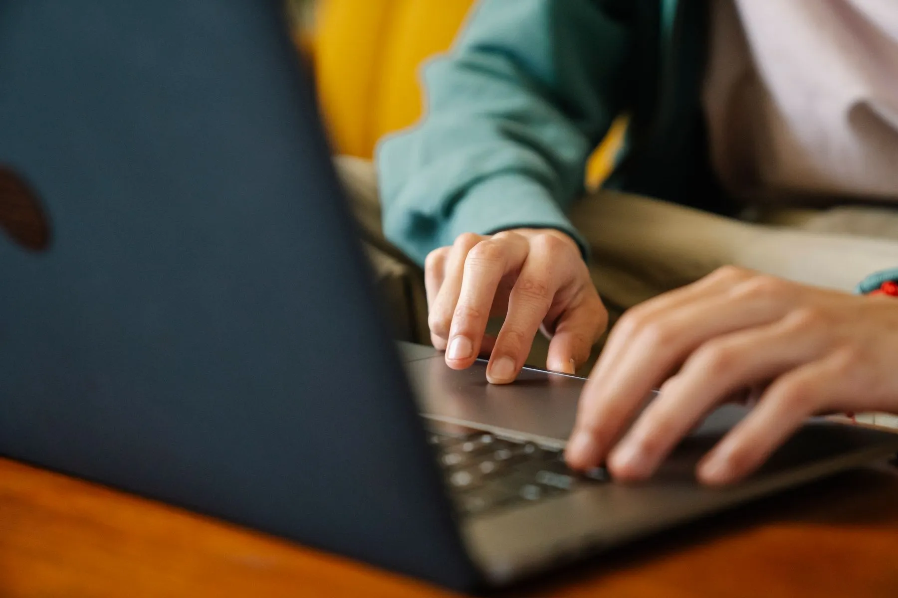 A person's hands typing on a laptop keyboard